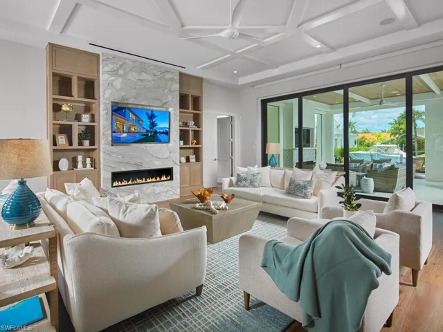 Living room featuring coffered ceiling, built in shelves, hardwood / wood-style floors, and a premium fireplace