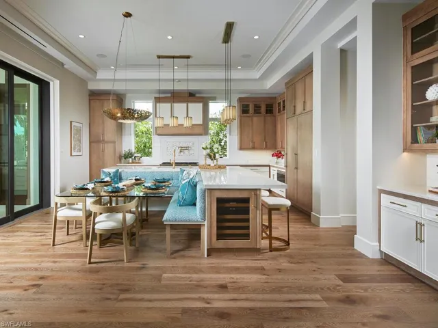Kitchen featuring wine cooler, a kitchen breakfast bar, a kitchen island with sink, decorative light fixtures, and hardwood / wood-style flooring