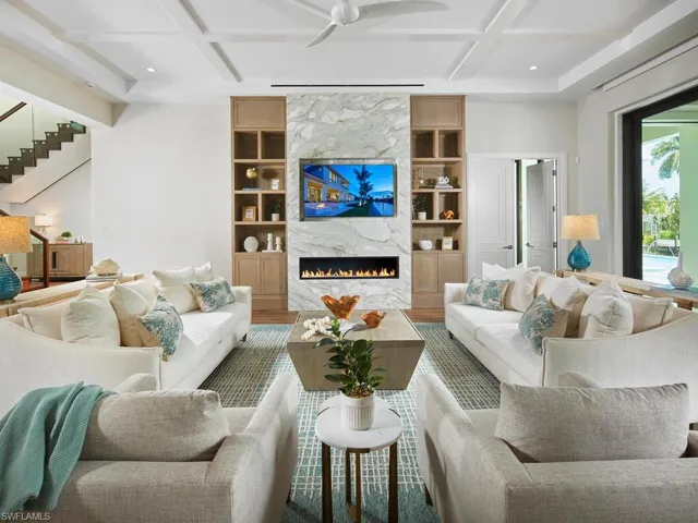 Living room with a high end fireplace, built in shelves, hardwood / wood-style floors, coffered ceiling, and ceiling fan