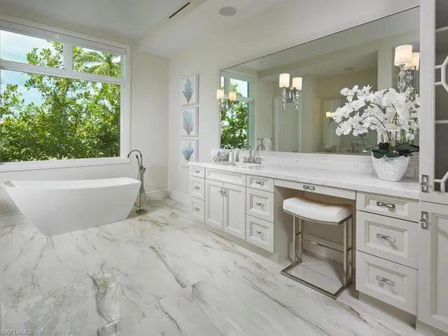 Bathroom with a bath, tile flooring, an inviting chandelier, and vanity