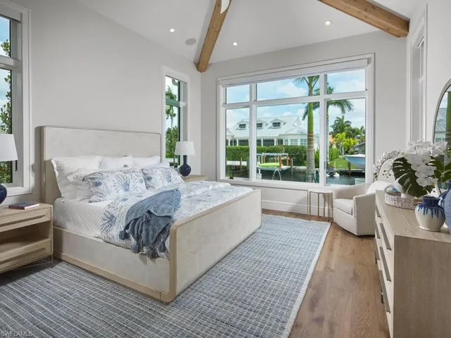 Bedroom featuring beam ceiling, dark hardwood / wood-style flooring, and a water view