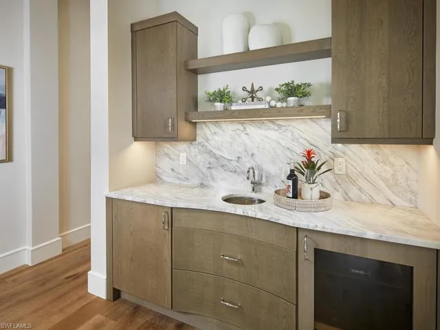 Kitchen featuring light stone countertops, sink, backsplash, and wood-type flooring