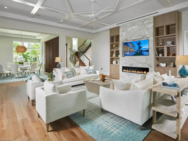 Living room featuring a fireplace, light hardwood / wood-style flooring, built in shelves, coffered ceiling, and ceiling fan