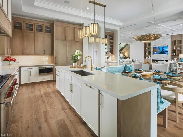 Kitchen featuring crown molding, custom exhaust hood, light wood-type flooring, a spacious island, and sink