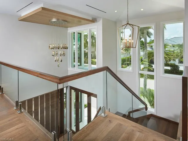 Stairway featuring a healthy amount of sunlight, hardwood / wood-style floors, and an inviting chandelier