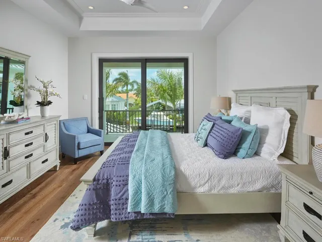 Bedroom with hardwood / wood-style floors, a raised ceiling, and access to exterior