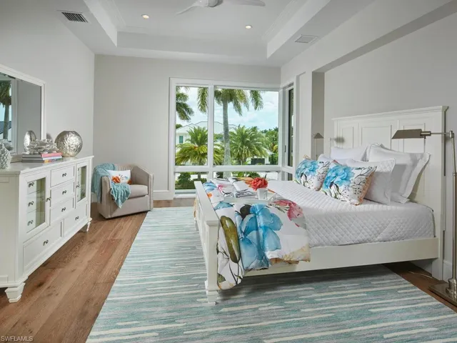 Bedroom with crown molding, hardwood / wood-style flooring, ceiling fan, and a raised ceiling