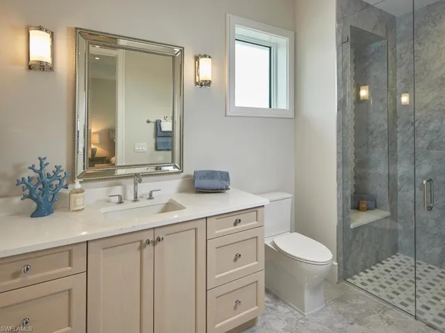 Bathroom featuring a shower with door, tile flooring, vanity, and toilet