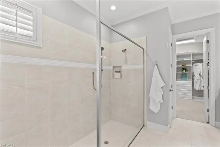 Glass-enclosed shower with a tiled surround, recessed shampoo niche, and an integrated bench