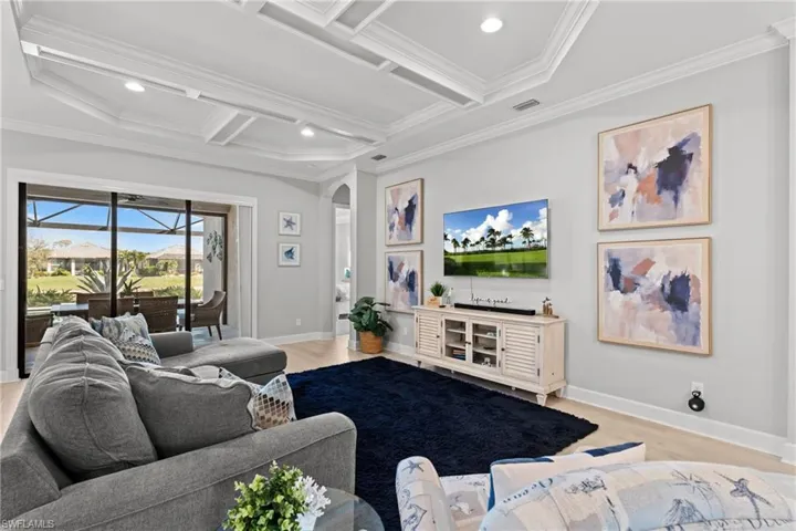 Tray ceiling with recessed lighting, wood-finish flooring, and sliding glass doors opening to a screened outdoor area