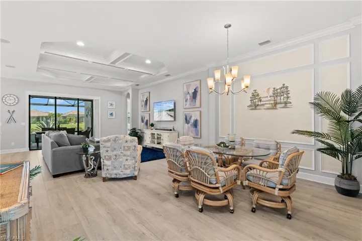 Expansive living area with wood-finish flooring, a coffered ceiling, and a chandelier
