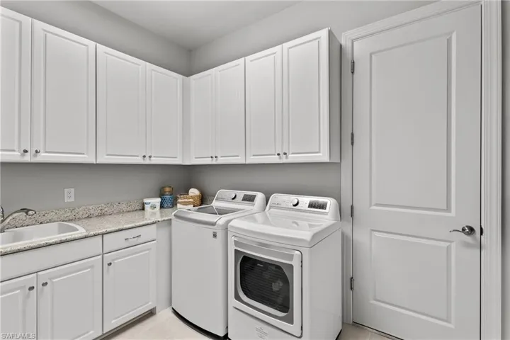 White shaker-style cabinetry, light speckled countertops, stainless steel sink, chrome faucet, and a paneled interior door