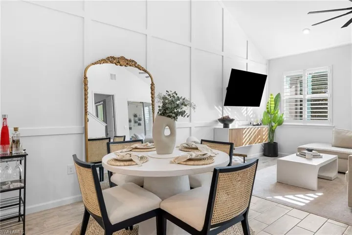 Dining space featuring wood finish floors, ceiling fan, vaulted ceiling, and a decorative wall