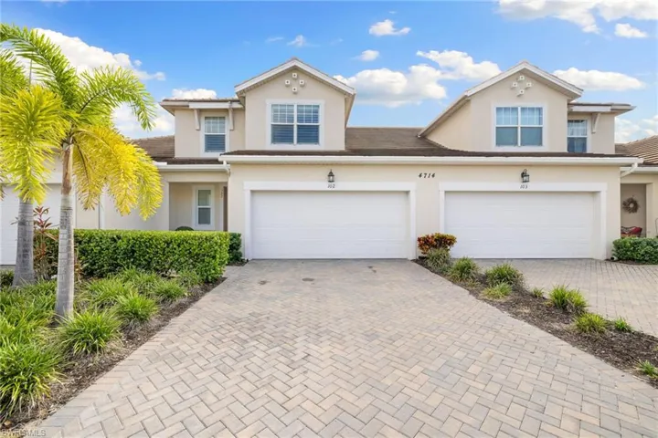 Traditional-style house with decorative driveway, stucco siding, and a garage