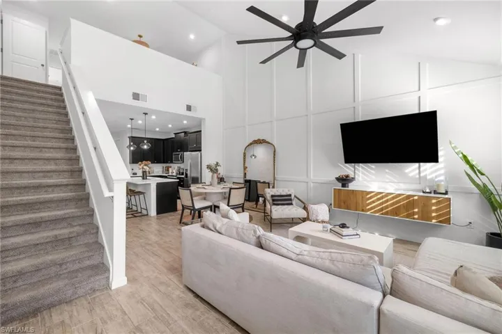 Living area with vaulted ceiling, a decorative wall, ceiling fan, recessed lighting, and light wood finished floors