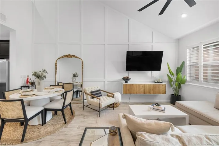 Living area featuring a decorative wall, ceiling fan, light wood finished floors, lofted ceiling, and recessed lighting