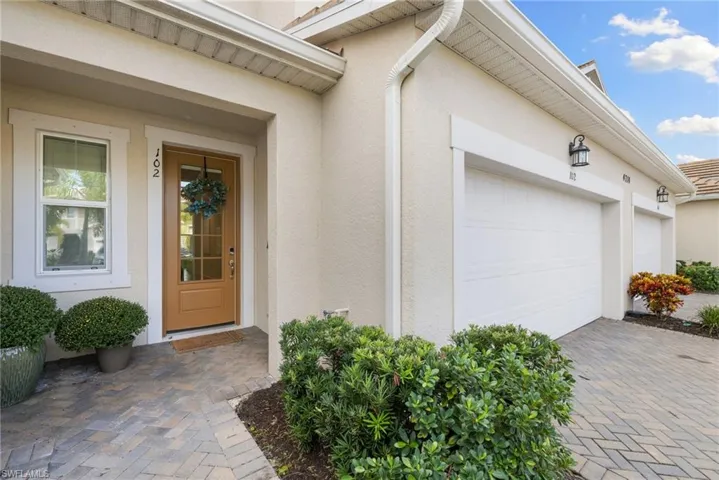View of exterior entry with stucco siding, decorative driveway, and an attached garage