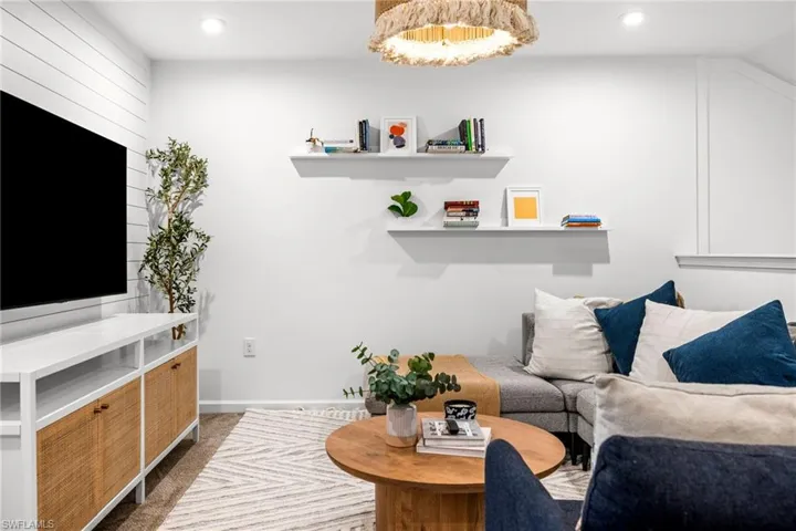 Living area with dark colored carpet and recessed lighting