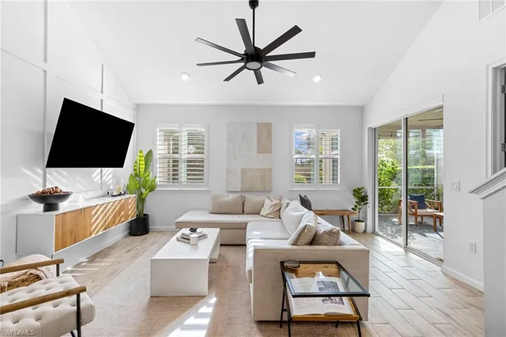 Living area featuring vaulted ceiling, wood finish floors, and a ceiling fan