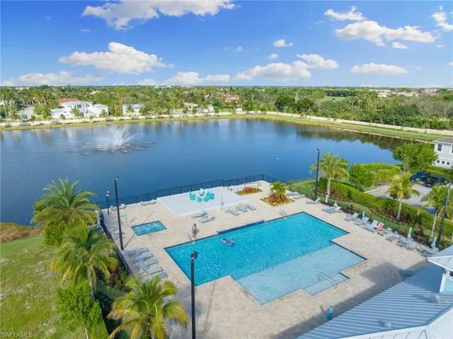 Community pool featuring a patio, a water view, and view of wooded area