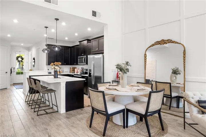 Kitchen with a breakfast bar area, a decorative wall, a center island, stainless steel appliances, and decorative light fixtures