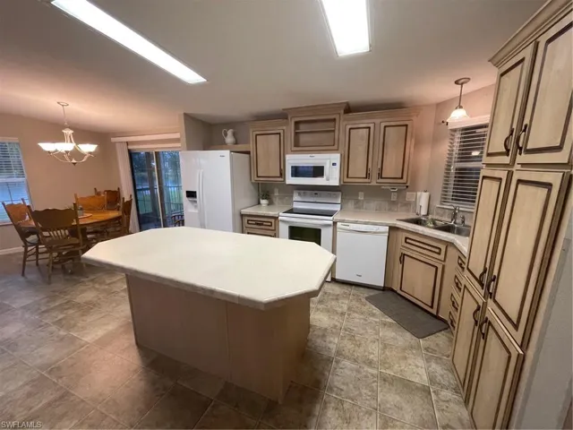 Kitchen featuring tile flooring, dishwashing machine, decorative light fixtures, sink, and refrigerator