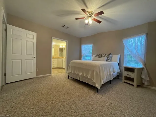 Bedroom with connected bathroom, ceiling fan, and carpet floors