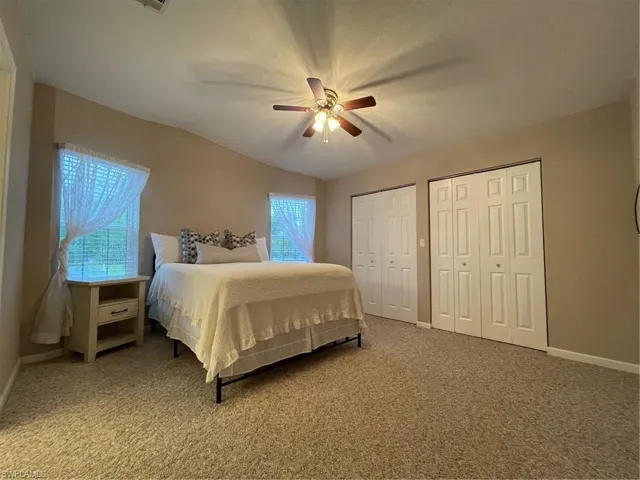Carpeted bedroom with multiple closets and ceiling fan