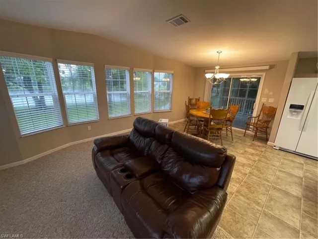 Tiled living room with an inviting chandelier and vaulted ceiling