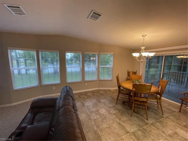 Tiled dining space with a wealth of natural light, a chandelier, and lofted ceiling