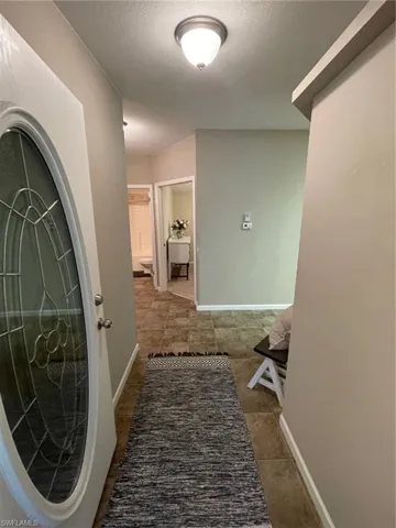 Hallway with tile floors and a textured ceiling