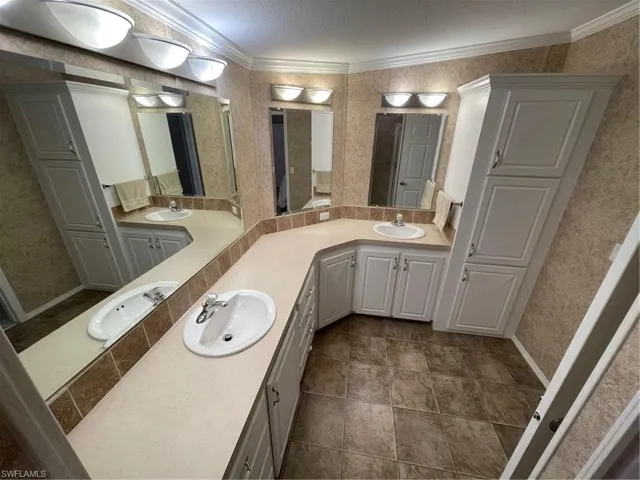 Bathroom with tile floors, crown molding, and double sink vanity
