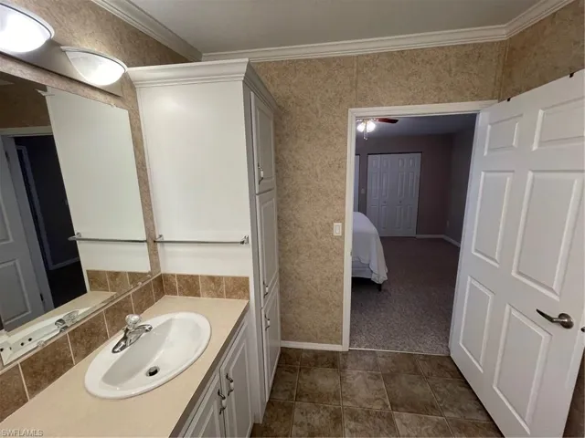 Bathroom featuring oversized vanity, ornamental molding, ceiling fan, and tile floors