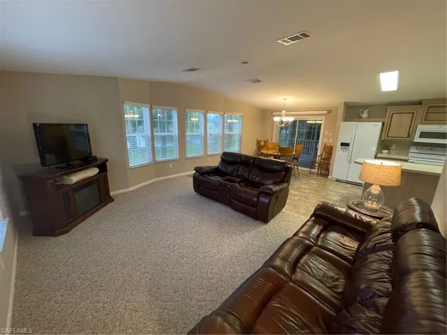 Carpeted living room with a notable chandelier and lofted ceiling