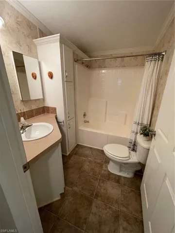 Full bathroom featuring shower / bathtub combination with curtain, ornamental molding, vanity, and toilet