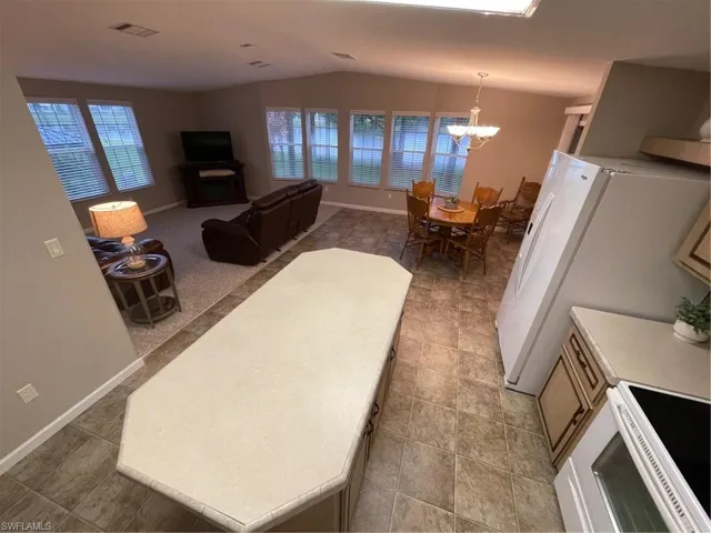 Tiled living room with a notable chandelier and vaulted ceiling