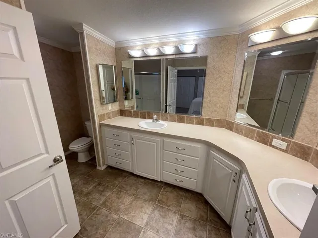 Bathroom with tile flooring, vanity, toilet, and crown molding