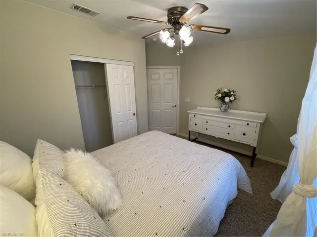 Bedroom with a closet, dark colored carpet, and ceiling fan
