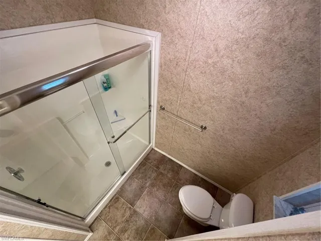 Bathroom featuring tile flooring, walk in shower, and toilet