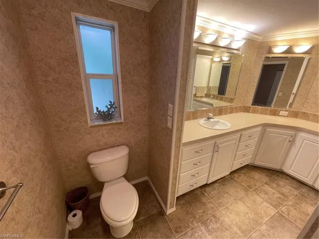 Bathroom featuring a textured ceiling, ornamental molding, tile floors, vanity, and toilet