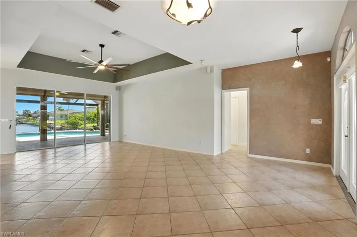 Unfurnished room with a tray ceiling, light tile patterned floors, and ceiling fan