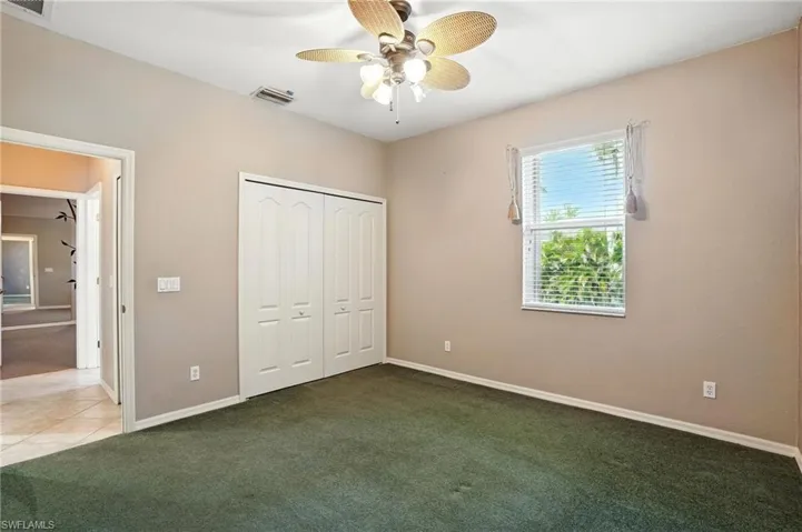 Unfurnished bedroom featuring carpet, a closet, and a ceiling fan