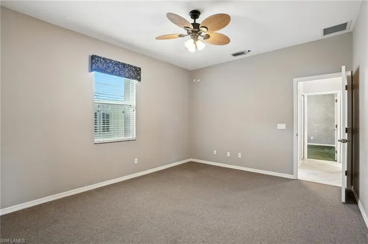 Carpeted spare room with baseboards and ceiling fan