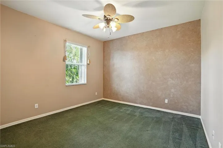 Empty room featuring dark colored carpet and ceiling fan