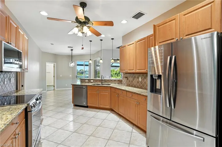 Kitchen with tasteful backsplash, appliances with stainless steel finishes, a peninsula, light stone counters, and recessed lighting