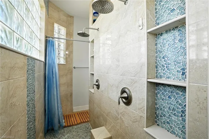 Bathroom with tiled shower and tile walls