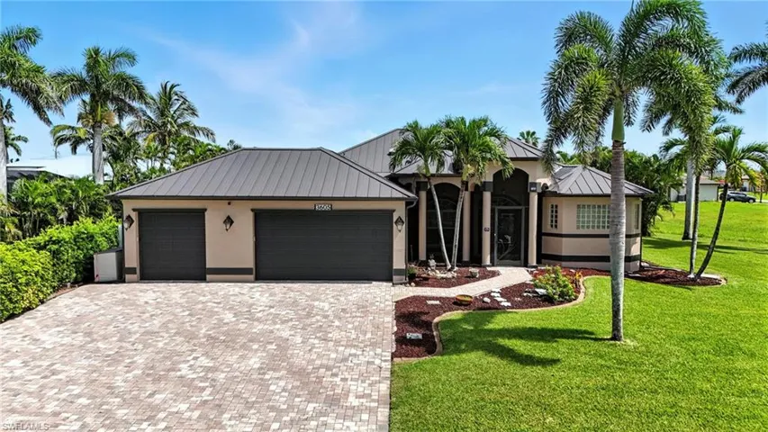 View of front of property with an attached garage, a metal roof, a standing seam roof, and driveway
