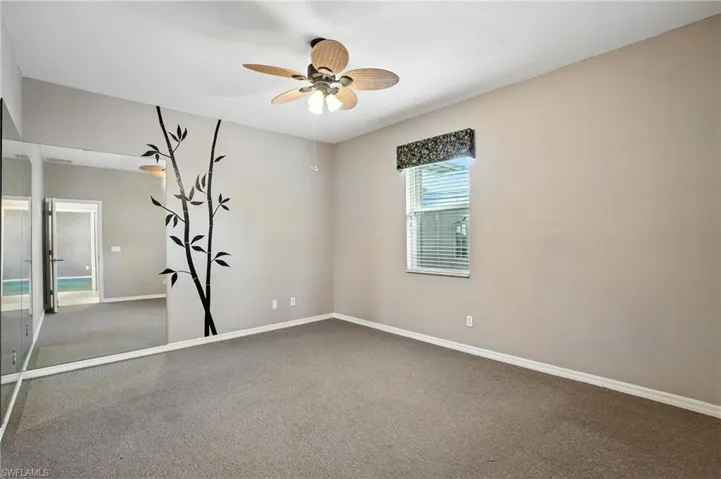 Carpeted empty room with baseboards and a ceiling fan