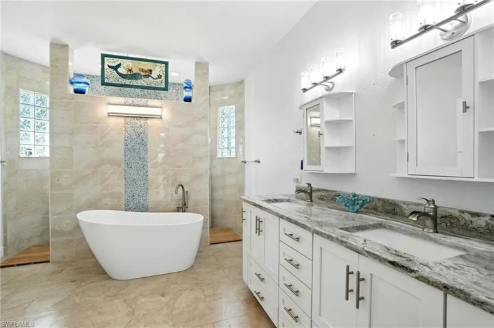 Full bathroom featuring double vanity, a walk in shower, and a freestanding tub