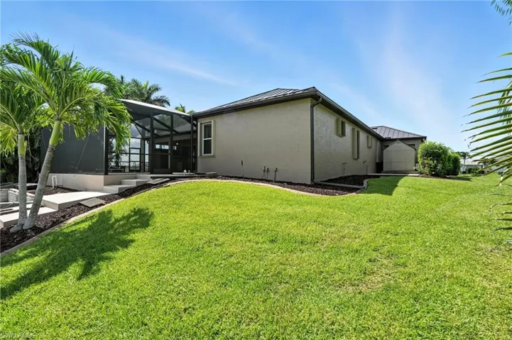 View of home's exterior featuring a standing seam roof, a yard, stucco siding, and a metal roof